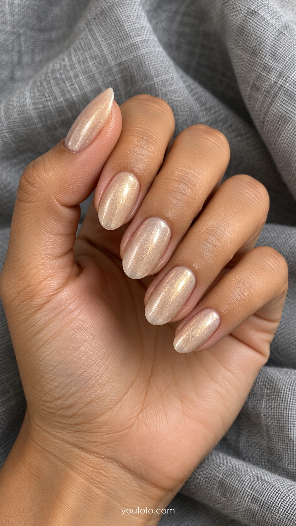 Medium oval nails pale warm champagne beige with fine golden pearl shimmer, no glitter flakes