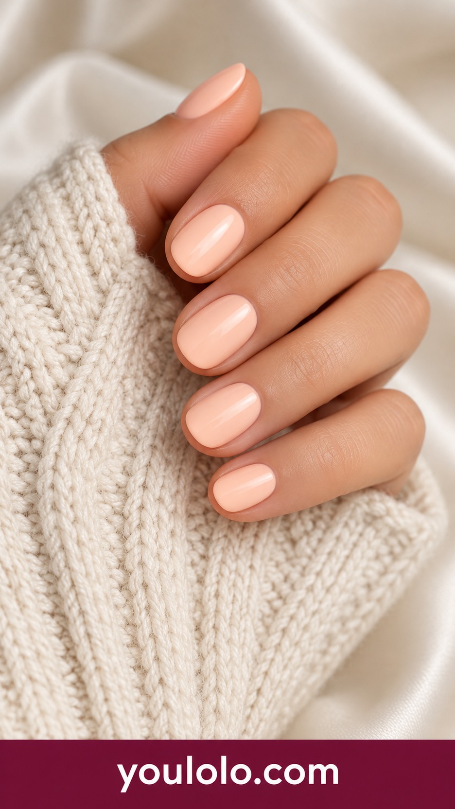 Very short round nails with uniform pale peach cream polish, no ombre on a naturally curled young adult hand