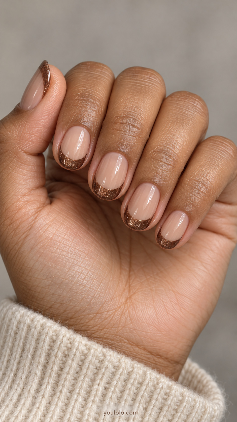Short oval nails: sheer beige nail beds and clearly painted cocoa brown magnetic French tips with diffuse bronze shimmer, slim curved smile lines.