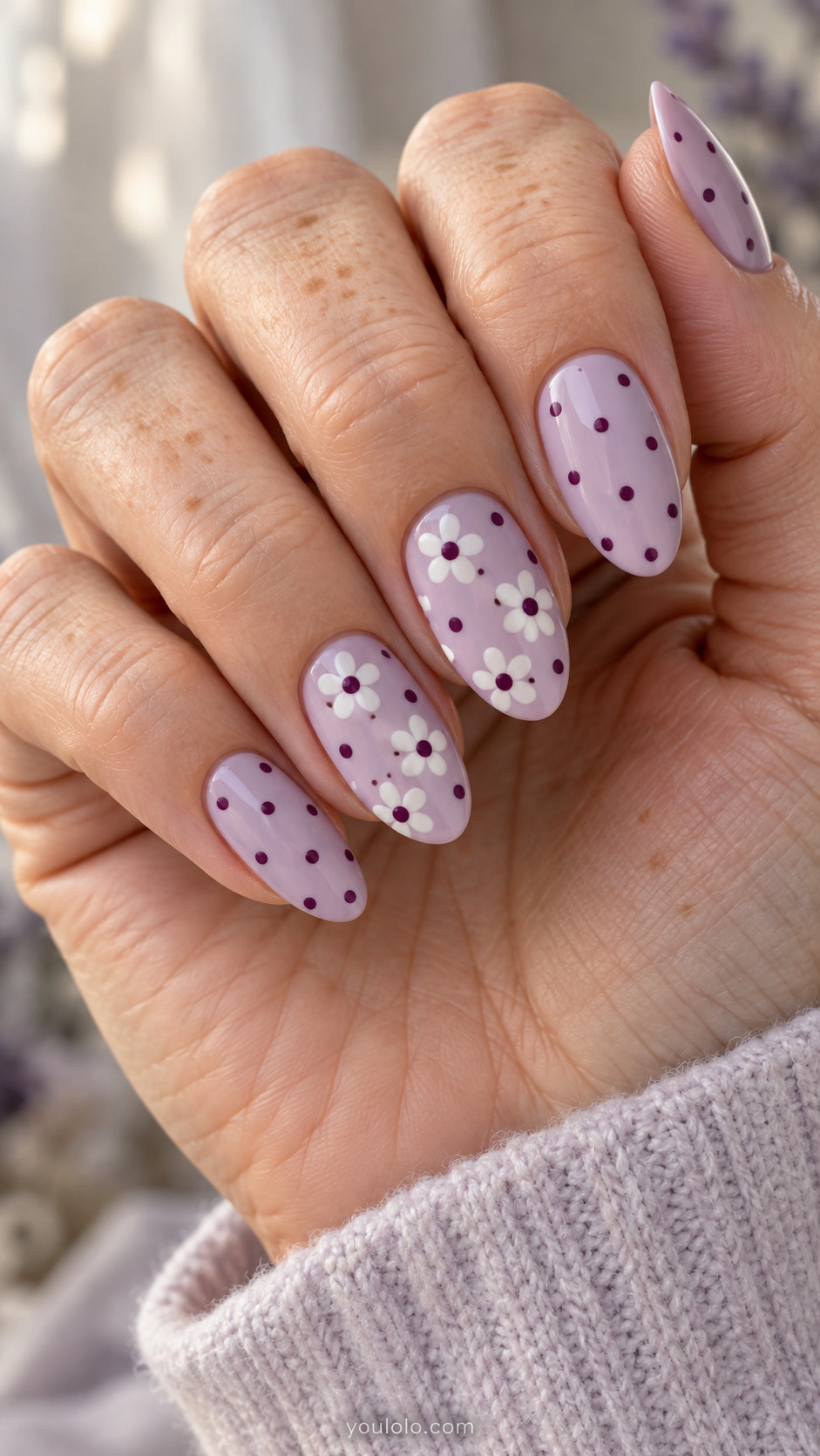 Almond lilac nails with plum dots and white dot-petal daisy accents.