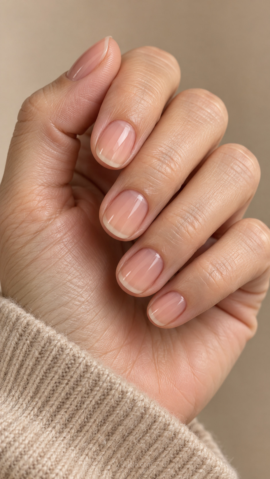 Very short round nails with sheer peach polish and subtly visible natural tips.