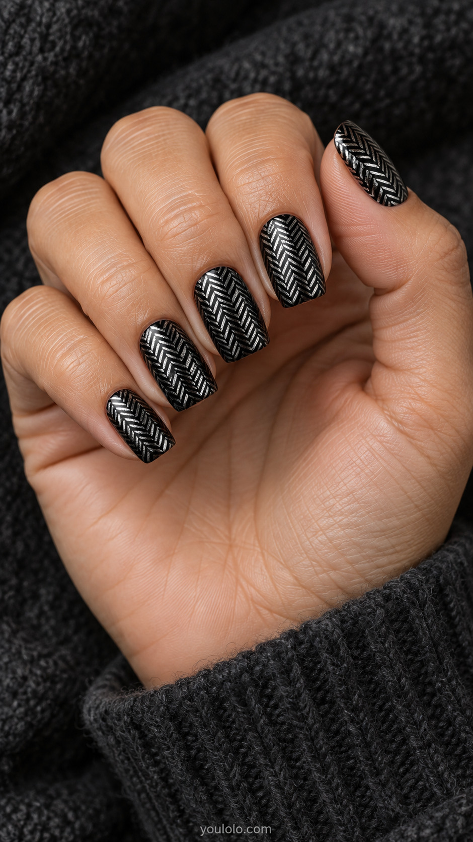 Medium square glossy black nails with narrow metallic silver herringbone chevrons across entire surface, small clean interlocking textile pattern