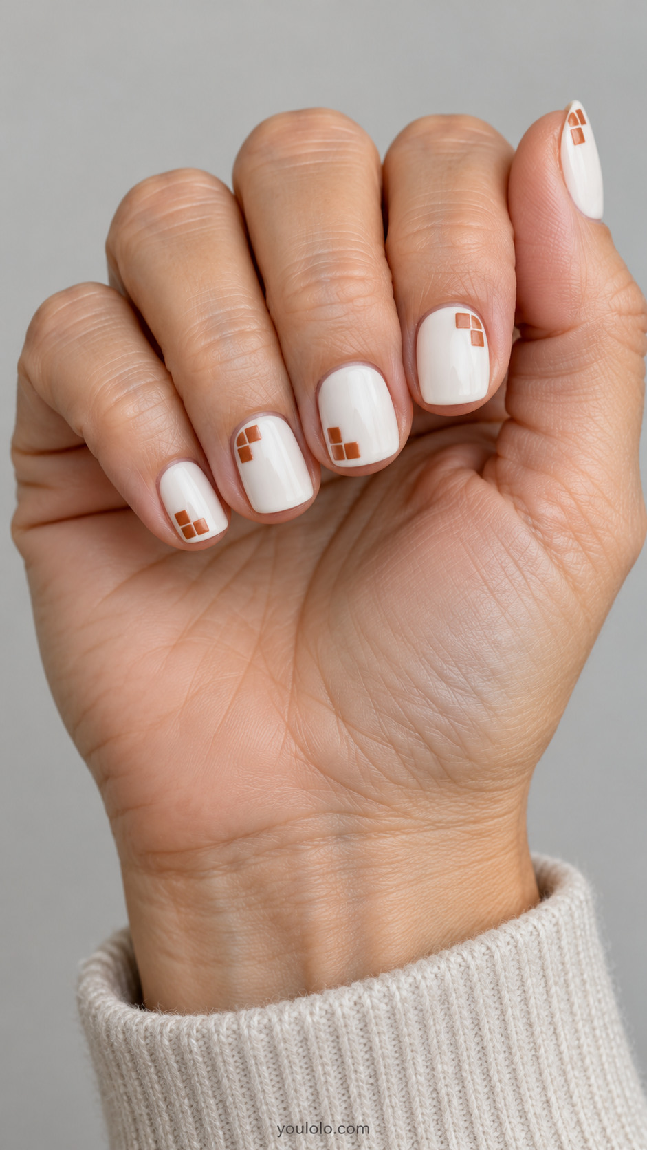Short white square nails with small terracotta tile clusters at the corners