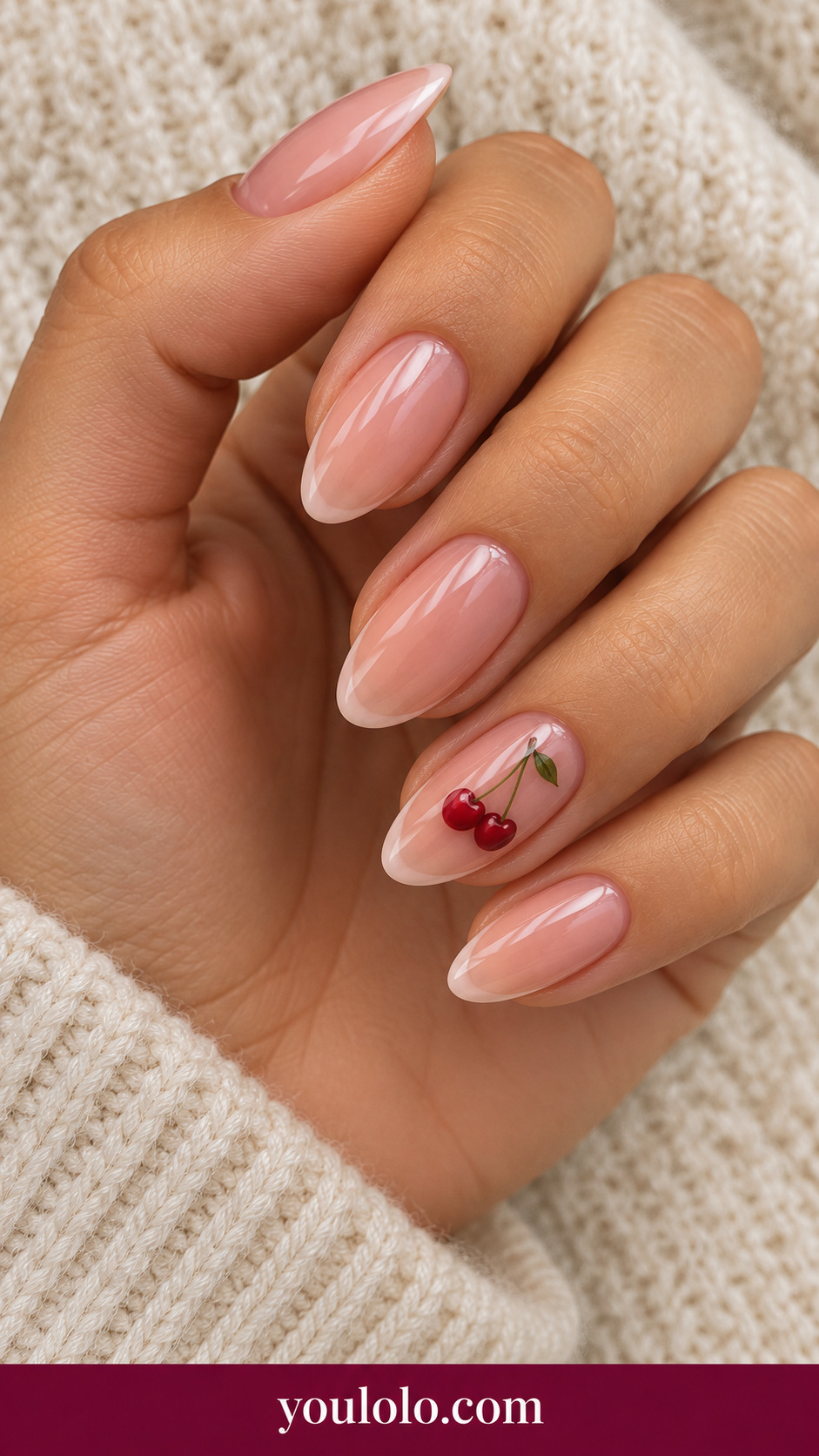 medium almond sheer pale blush press-on nails with miniature two red cherries and fine green stem on ring nail only, remaining plain sheer blush on a naturally posed adult female hand