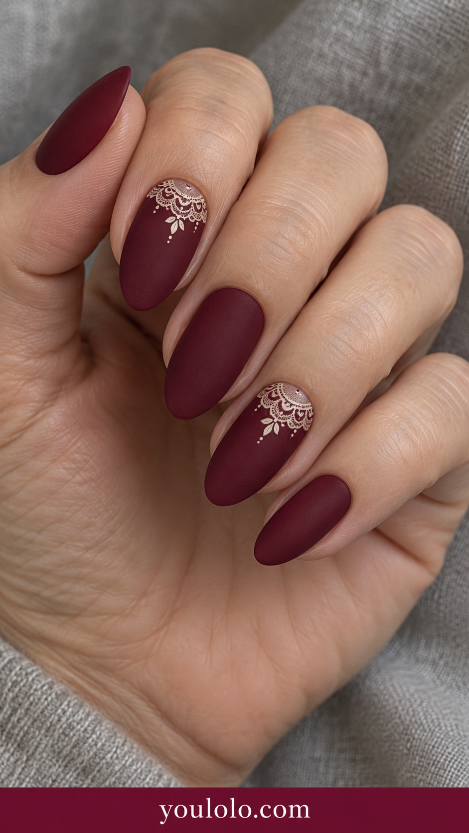 medium almond cranberry nails with delicate flat ivory scalloped lace along base of two accents, rest plain cranberry satin on a naturally relaxed adult hand