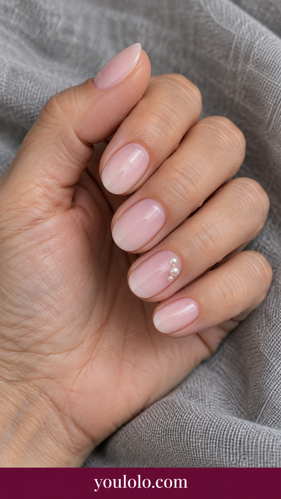 Pearl Micro Cluster: short oval milky pink nails ring nail cluster of three extremely tiny ivory pearls near side, other nails plain on a naturally posed adult hand