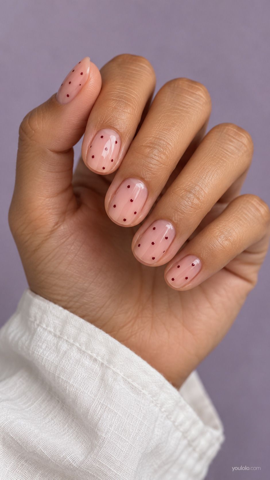 Short natural oval nails, transparent rosy nude base, sparse tiny burgundy dots scattered with deliberate open space, a few dots per nail.