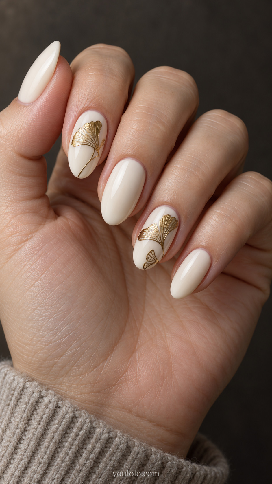 Medium almond ivory nails with finely detailed gold ginkgo leaves on the index and ring nails