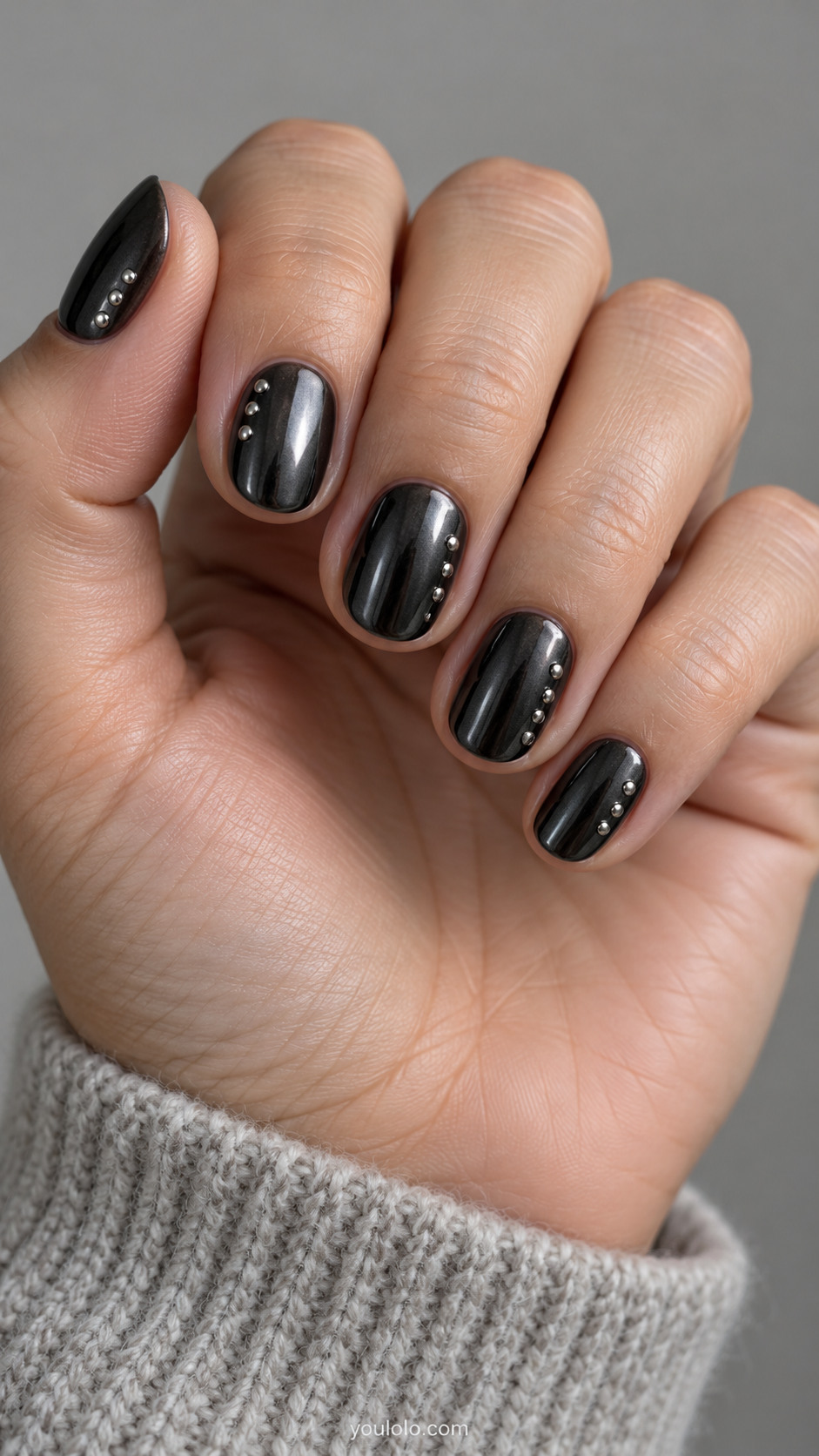 Short oval dark black chrome nails with tiny flat silver metal studs in one uneven trail along alternating sidewalls, only three to five studs per nail