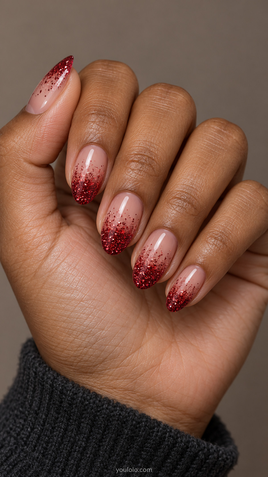 Almond nails with sheer pink bases fading into ruby glitter tips