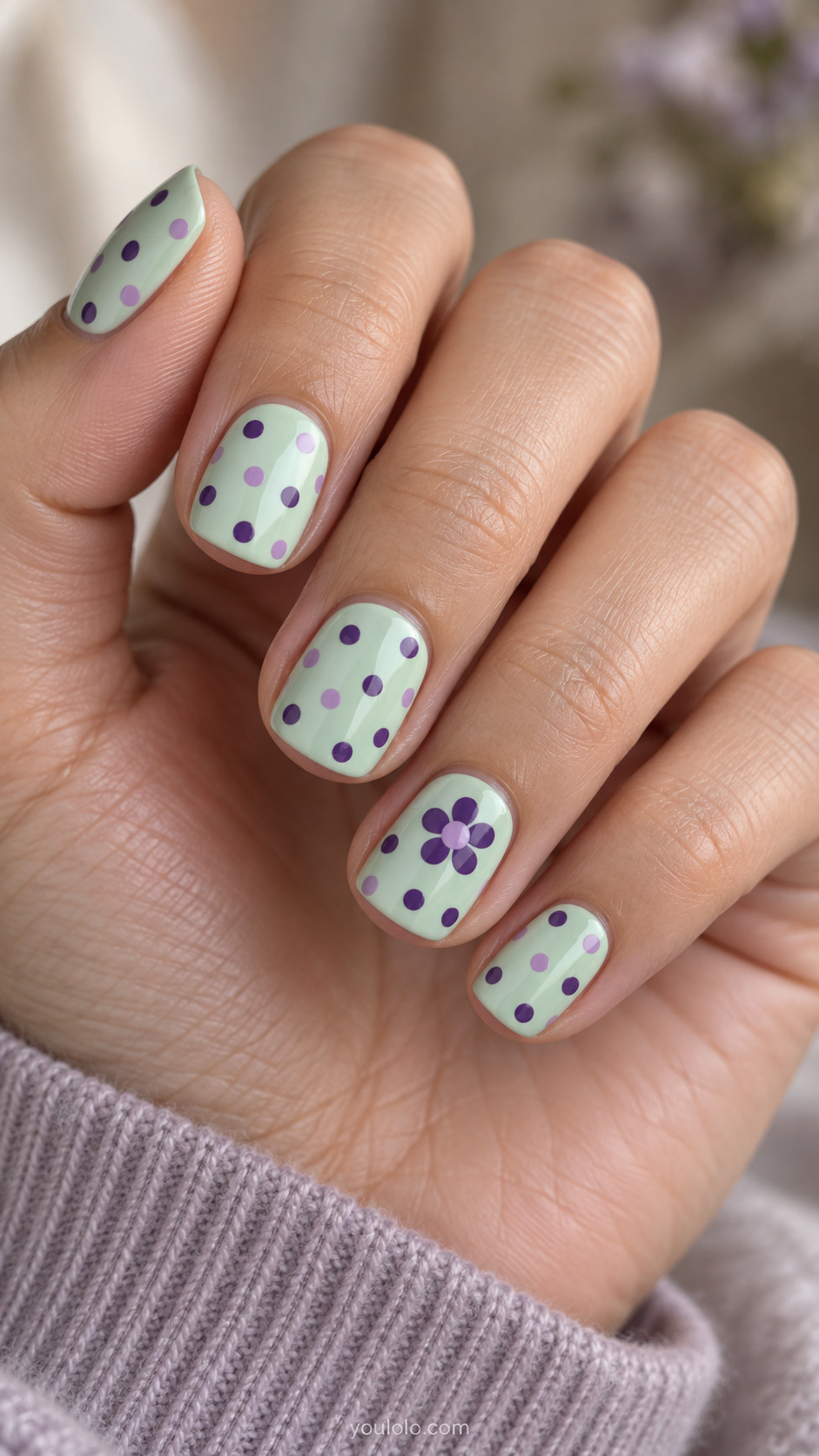 Short mint nails with violet and lilac dots and a violet flower accent.