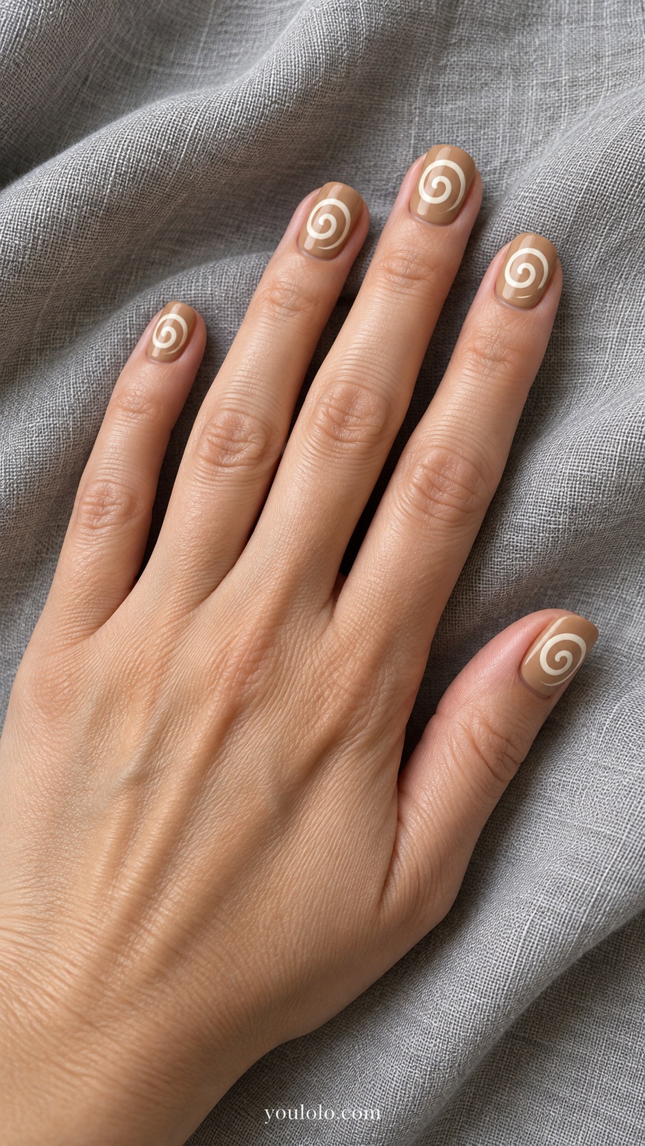 Short oval nails creamy tan base one simple ivory spiral on each nail resembling cinnamon rolls flat paint