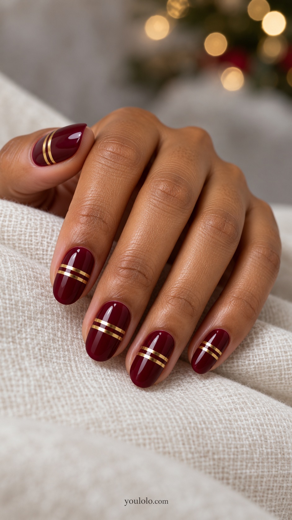 Medium oval burgundy nails two parallel gold chrome transverse bands near middle