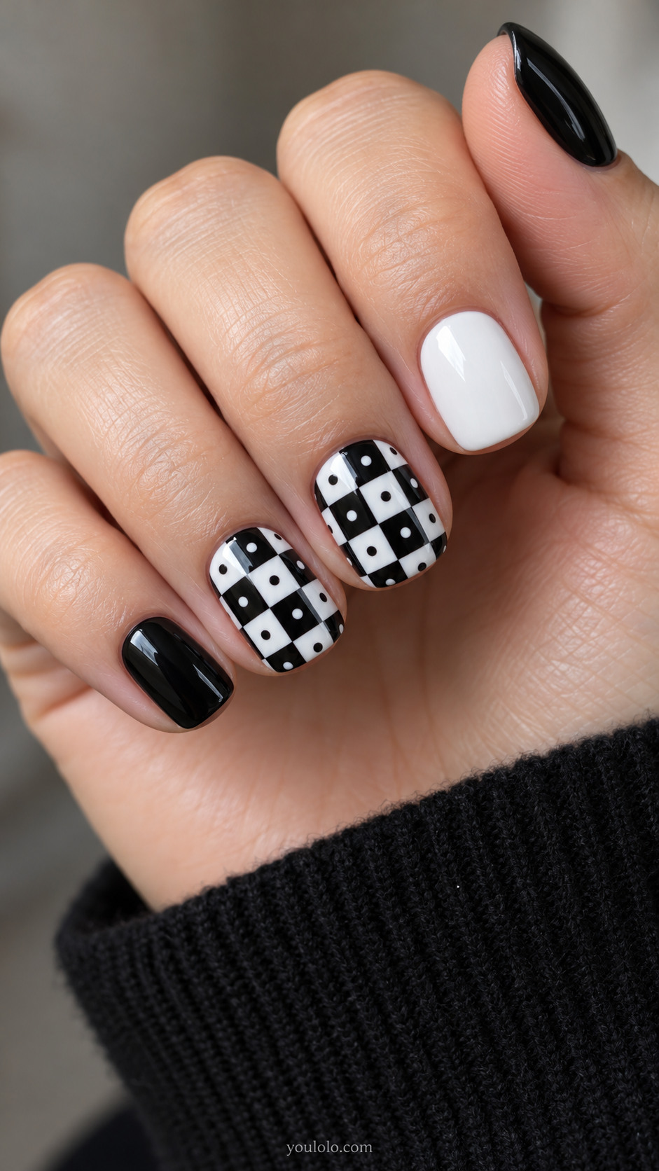 Black-and-white checkerboard accent nails with contrasting dots beside solid nails