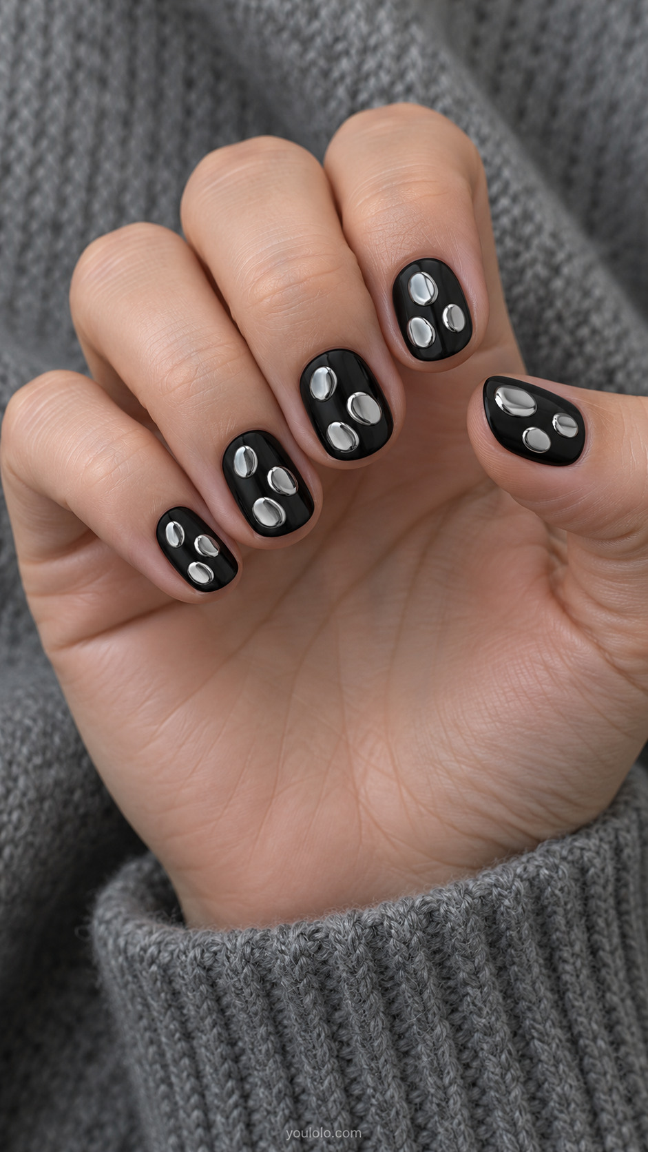 Short round black nails with three irregular small flat reflective silver chrome pebble shapes per nail, different placements with generous black gaps, flat polish no raised stones