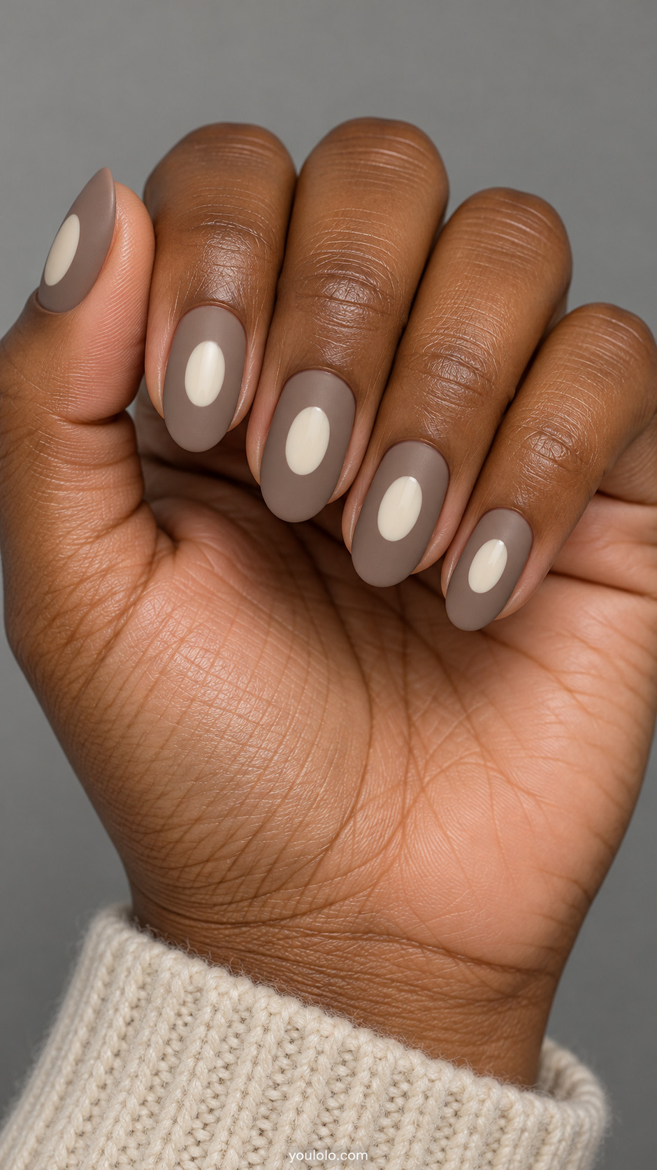 Matte mushroom taupe nails with one small glossy ivory oval medallion centered on each nail, clean hard edges, no gradient.
