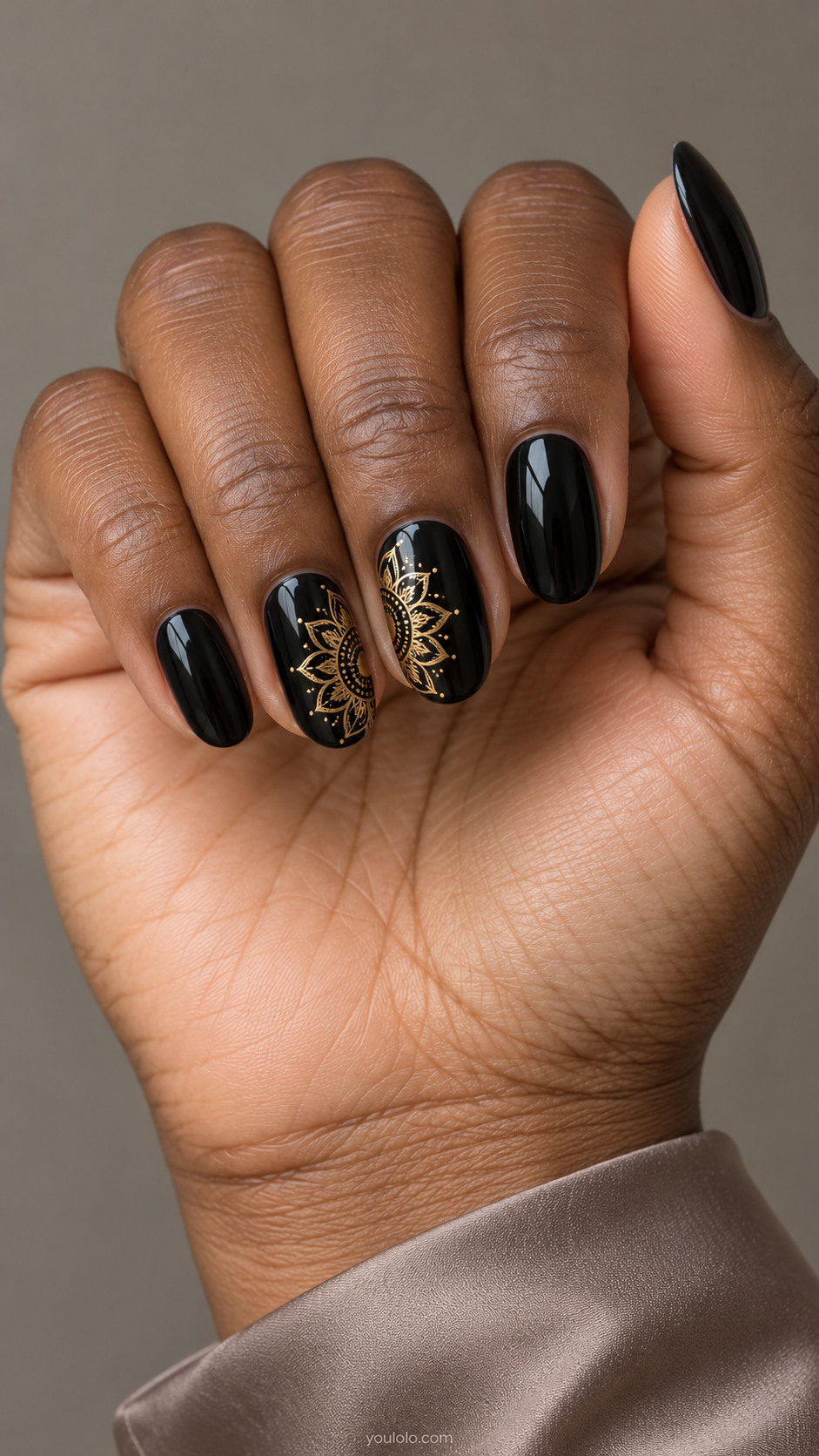 Glossy black oval nails with gold mandala flowers cropped along the sides