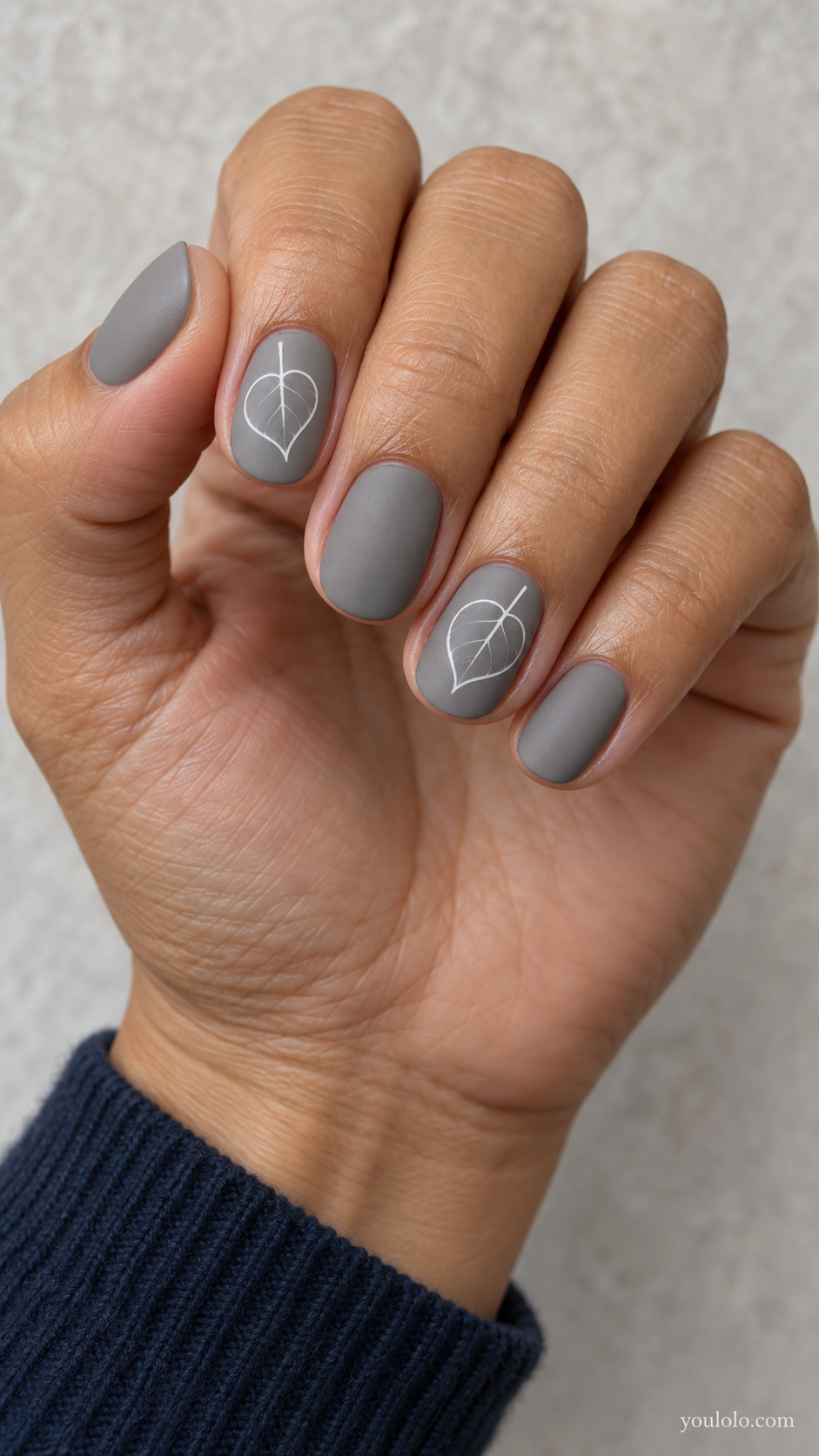 Short oval nails with matte warm grey nails with white outline-only round heart-shaped aspen leaves on alternating nails, single delicate white vein per leaf, no filled leaves.