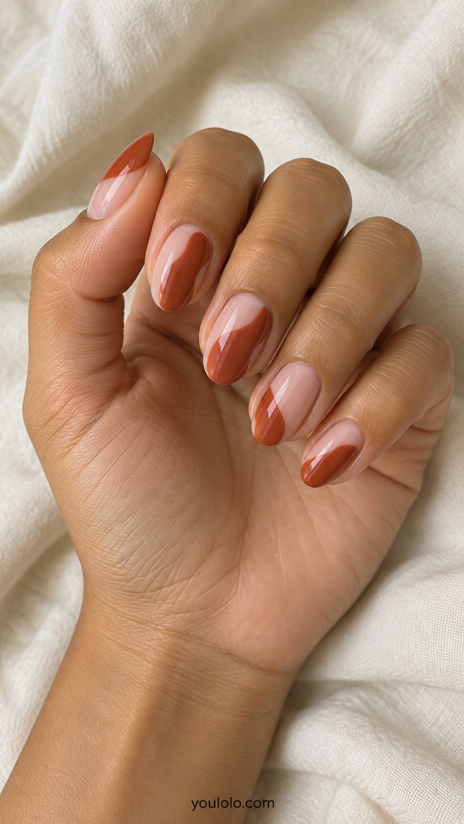 Medium oval nails translucent neutral pink base with rust irregular curved blocks covering half of each nail