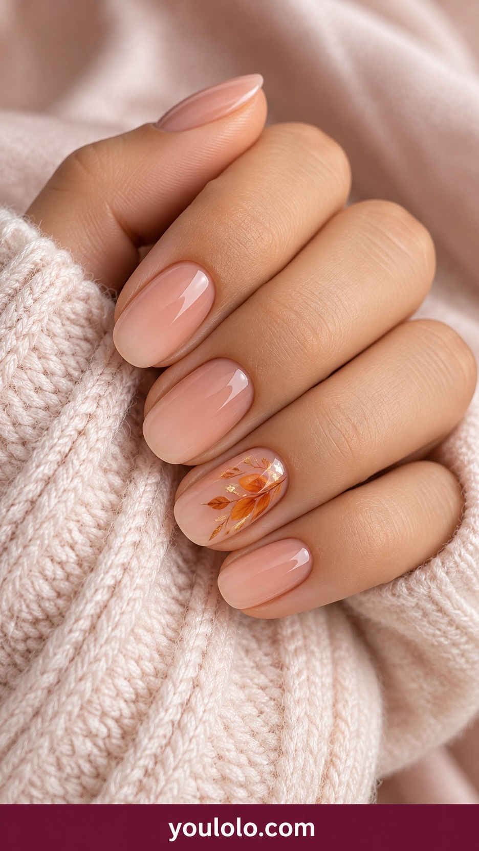 Short oval warm nude nails with small saffron orange and gold botanical sprig with petals and leaves painted on one accent on a naturally curled young adult hand