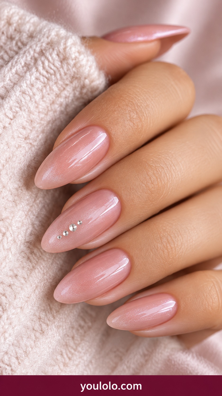 Medium almond sheer cool pink nails with three tiny silver crystal dots in a vertical line on one accent and subtle white shimmer elsewhere on a naturally curled young adult hand