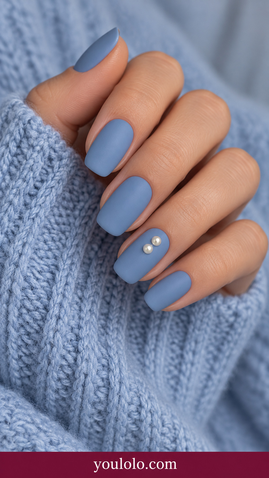 medium squoval muted denim blue nails two tiny low-profile ivory pearls in vertical line on ring nail only on a naturally relaxed adult hand