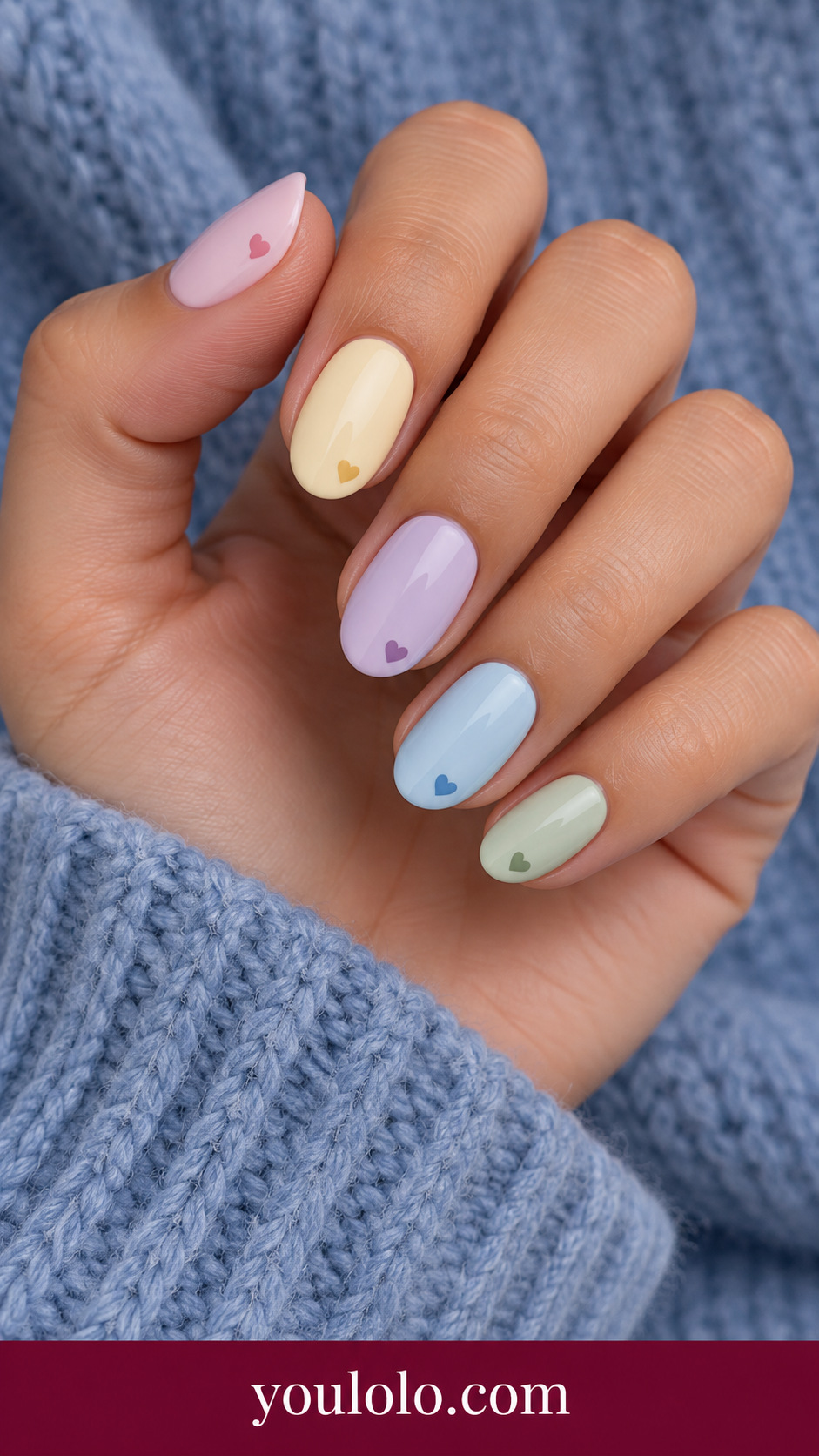 Pastel Heart Skittle: short oval nails five soft pastel cream colors each one tiny contrasting pastel heart near tip on a naturally posed adult hand