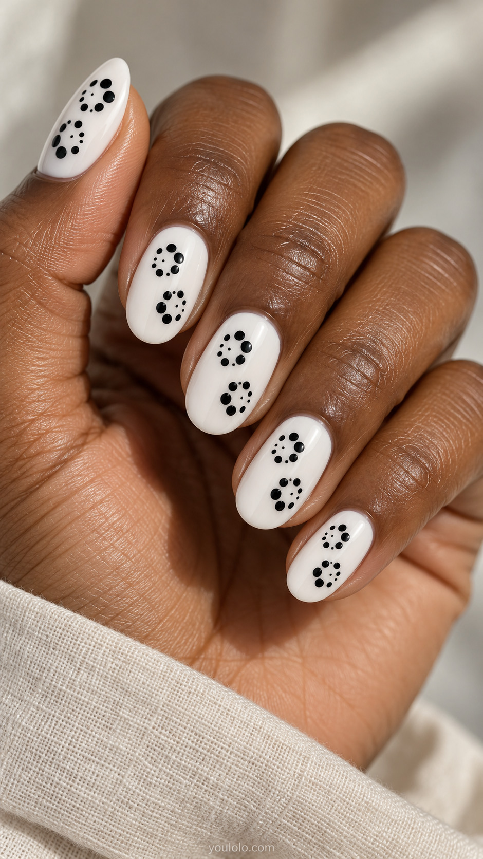 Medium oval white nails each with two small pinwheel clusters of five graduated black circles arranged around empty center, flat graphic no petals