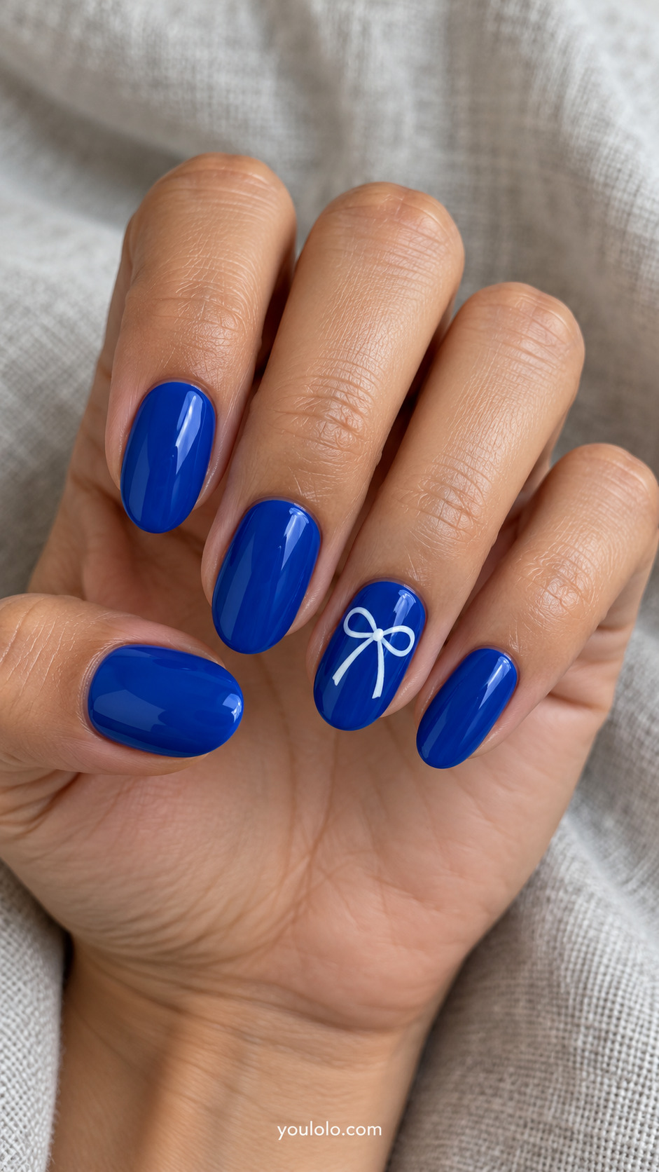 Royal blue oval nails with a fine white painted ribbon bow