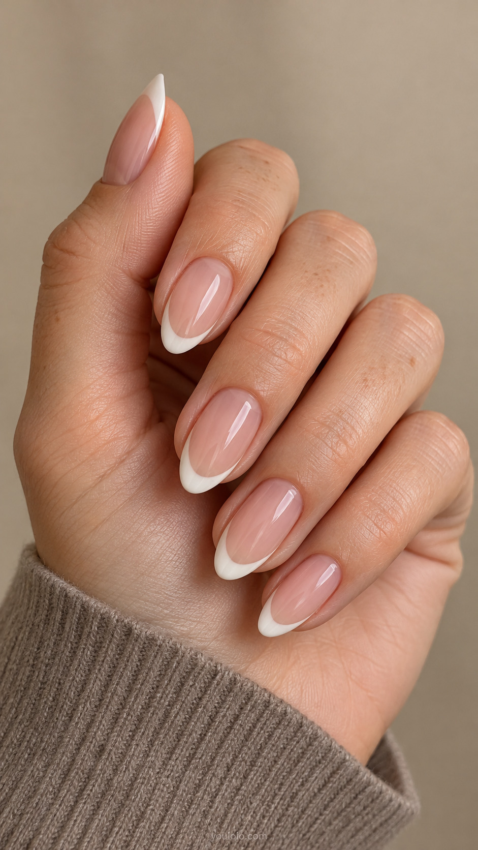 Medium almond nails with a sheer rosy base and narrow curved ivory French tips.