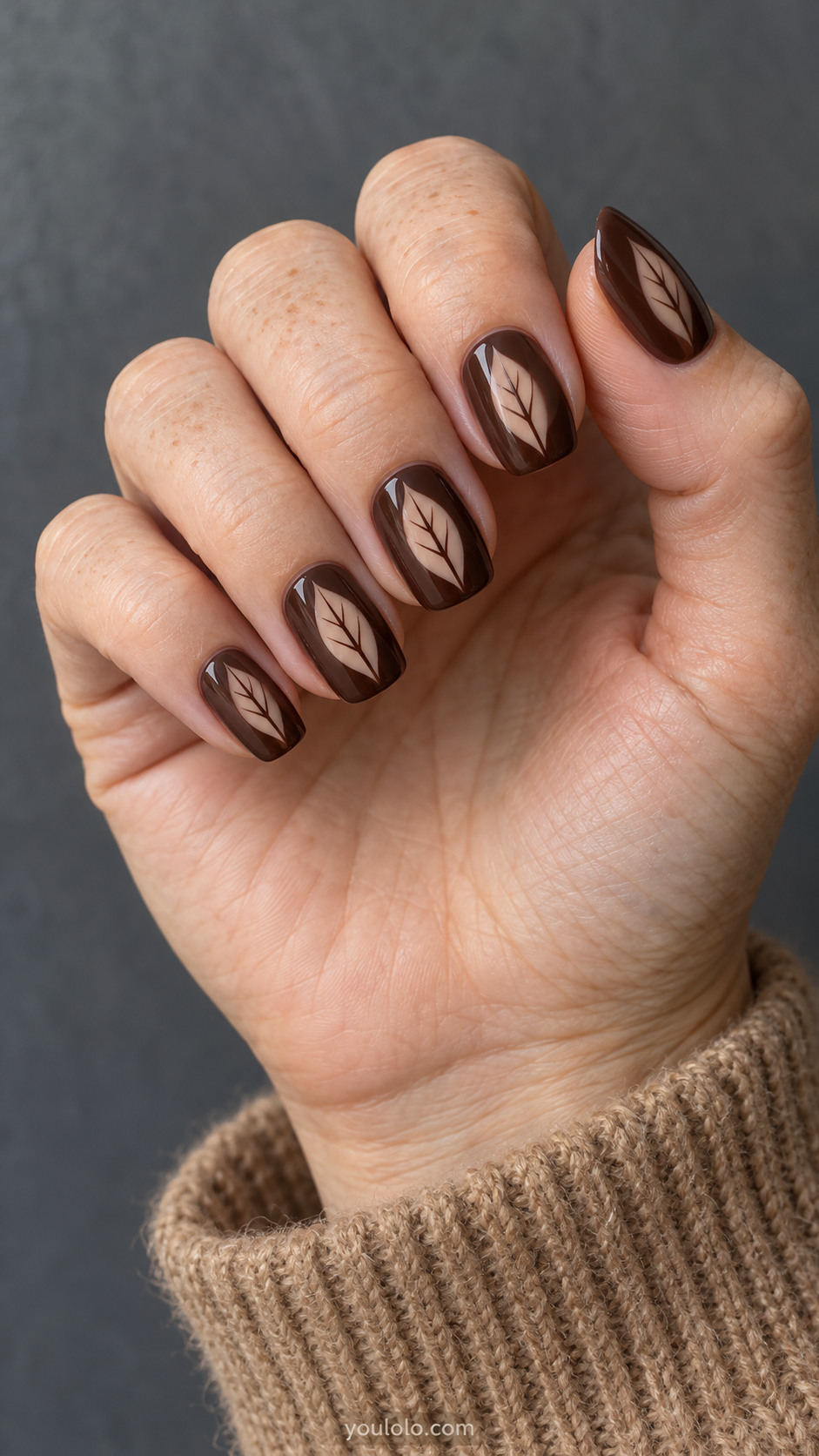 Medium rounded square nails with espresso brown opaque nails with a single leaf-shaped clear negative-space window in center of each nail; oval leaf silhouette and fine espresso central vein.