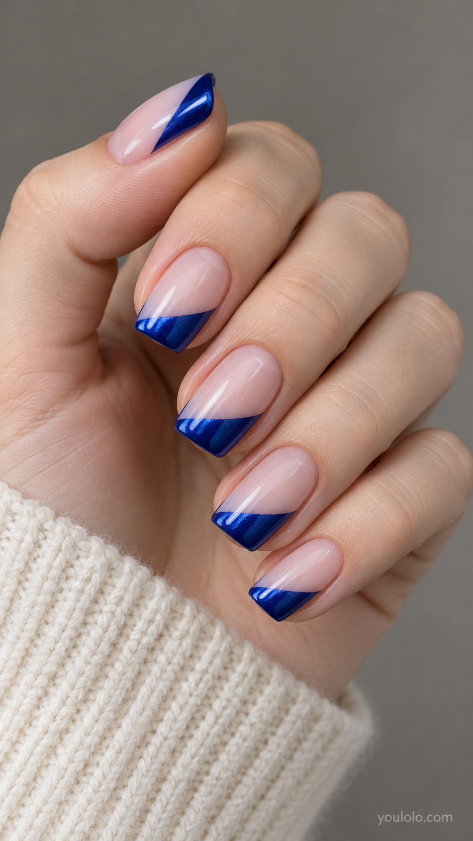 Slanted Sapphire French Tips on a softly gathered feminine hand with detailed sapphire blue manicure