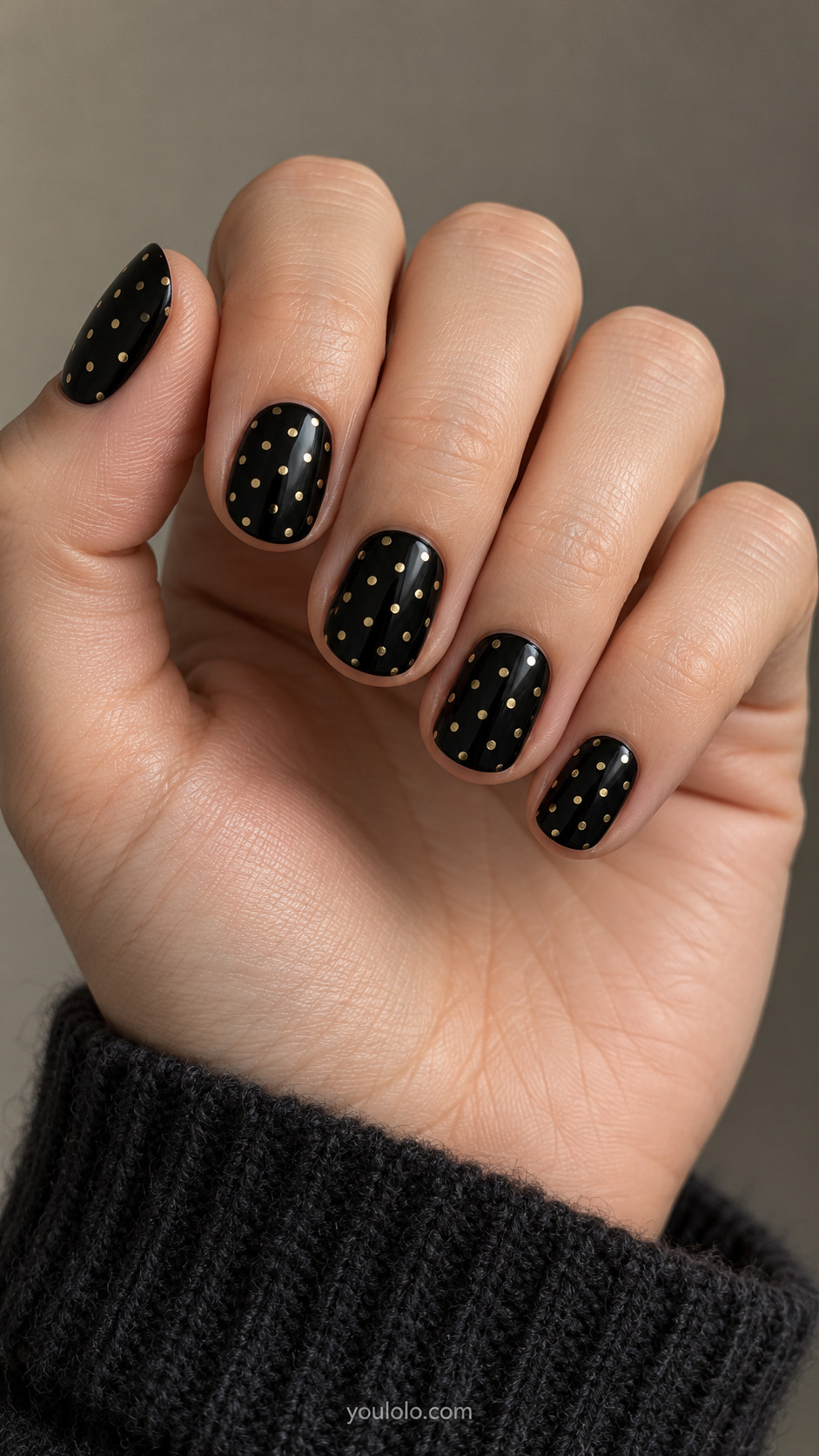 Short rounded black nails covered with evenly spaced tiny gold dots