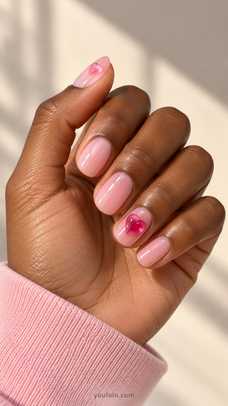 Gummy-Heart Accent Nails — Short oval nails, glossy milky strawberry-pink base, one translucent red raised gummy heart centered on ring nail and one tiny pink heart on thumb, other nails plain pink, rounded low relief