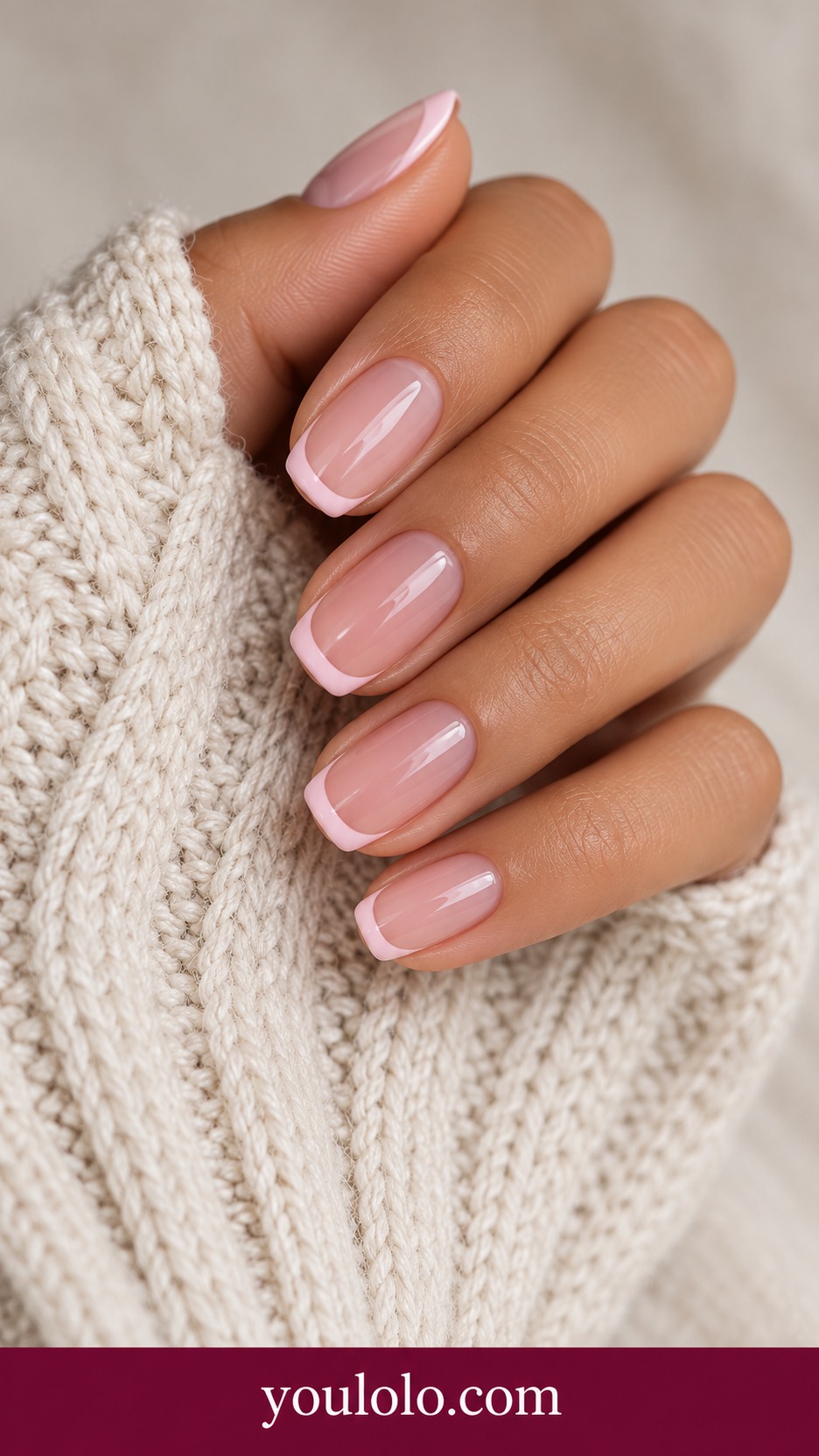 Short squoval translucent rose nails with fine pale blush pink French tip instead of white on a naturally curled young adult hand