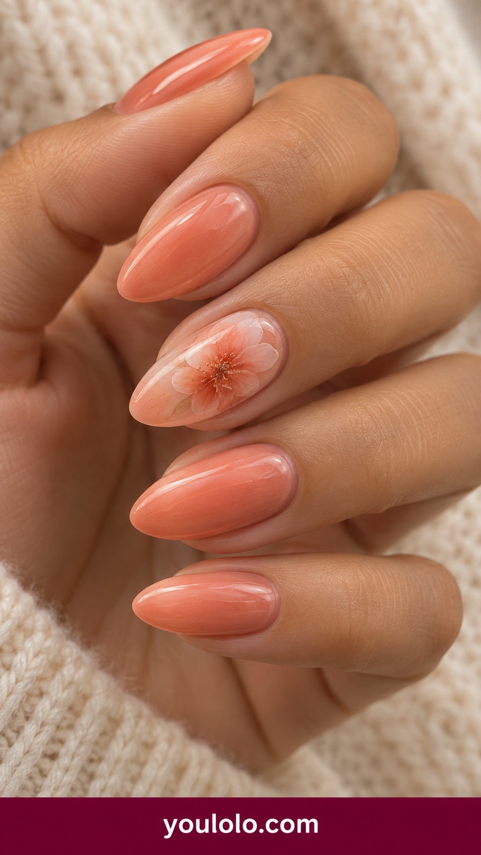 Medium oval pale coral nails with translucent peach watercolor flower on one accent on a naturally curled young adult hand