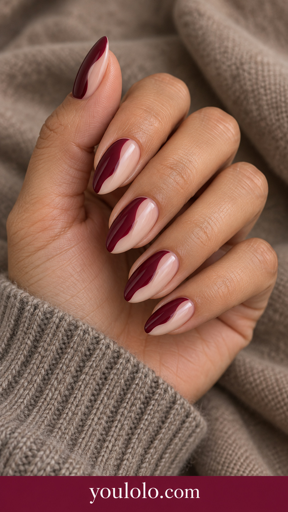 Wine Nude Wavy Split: medium almond nails maroon one side sheer beige other side divided by smooth vertical wavy boundary on a naturally posed adult hand