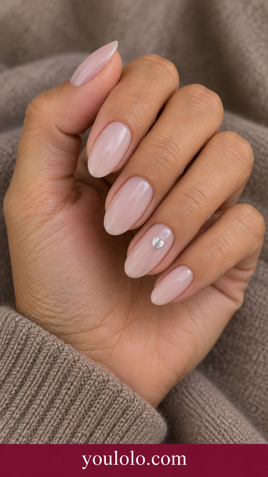 Silver Heart Thread: medium oval cool nude nails one tiny flat silver heart with fine trailing silver line on ring nail on a naturally posed adult hand