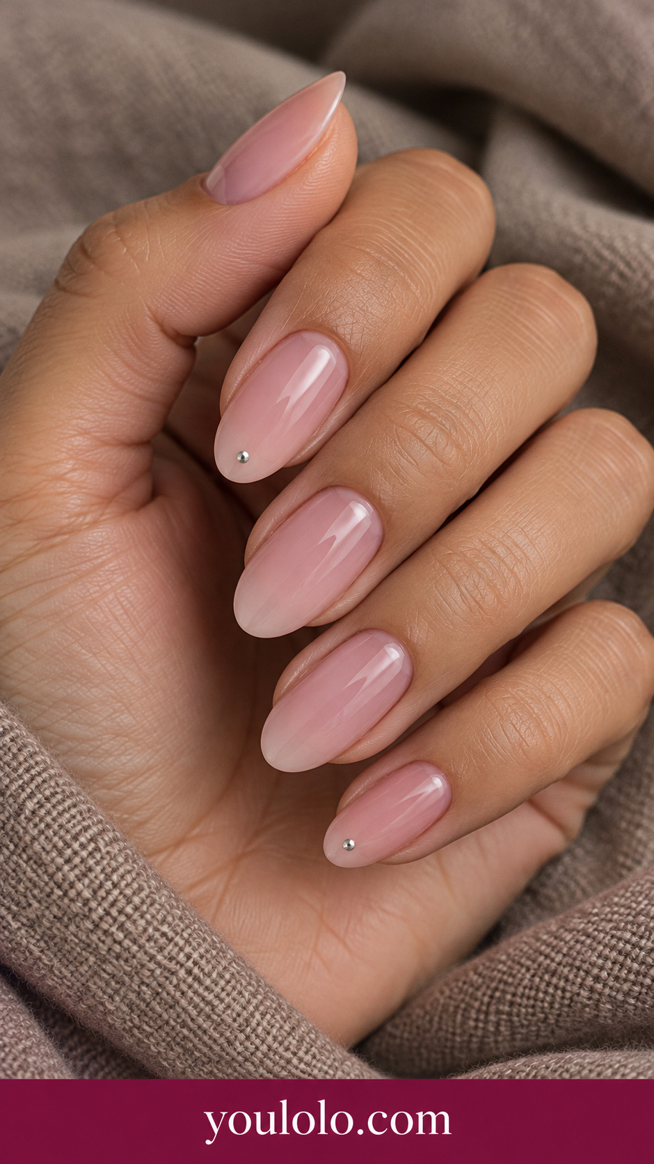 Rose Silver Pin Dot: medium oval translucent rose nails one tiny silver pin-dot stud centered near tip on two nails on a naturally posed adult hand
