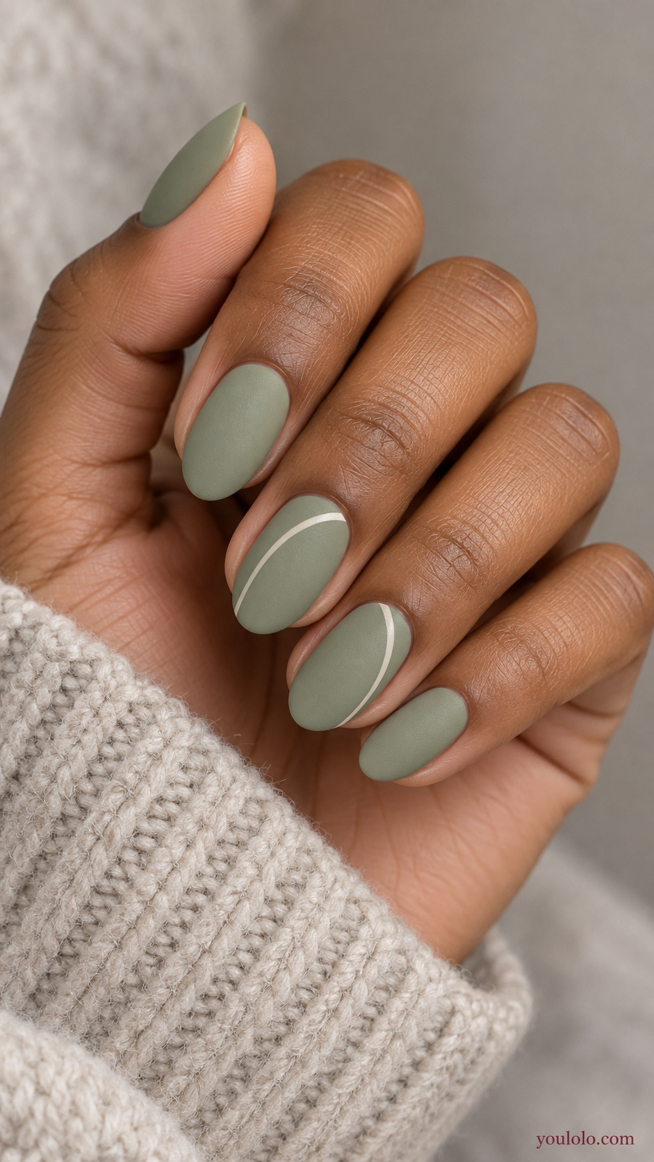 An Off-Center Ivory Arch on a softly gathered feminine hand with a matte green manicure