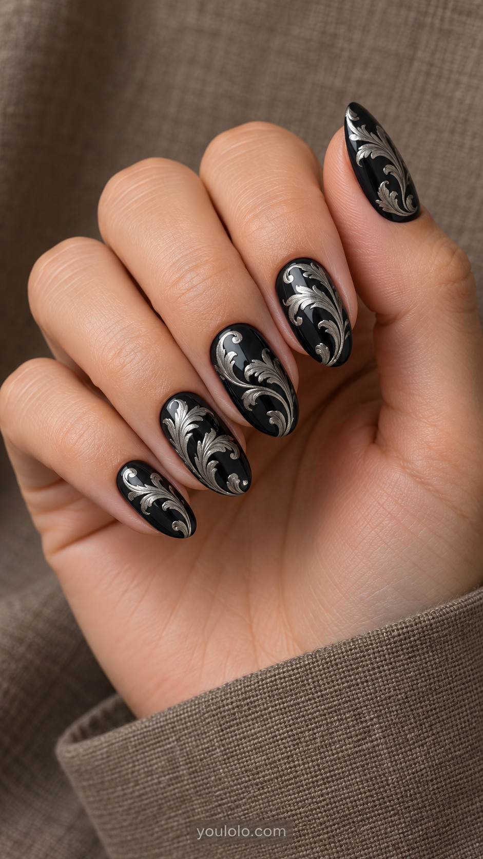 Medium almond black glossy nails with metallic silver acanthus leaf scroll painting forming elegant S shapes, fine curved botanical detail