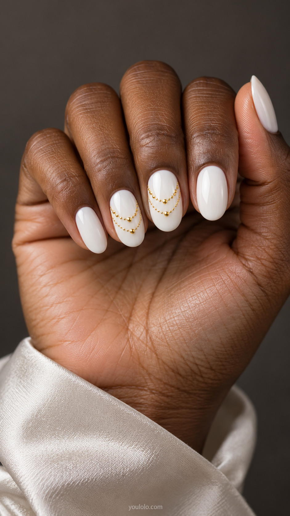 Medium oval white nails with tiny low-profile gold bead drapes on the middle and ring nails