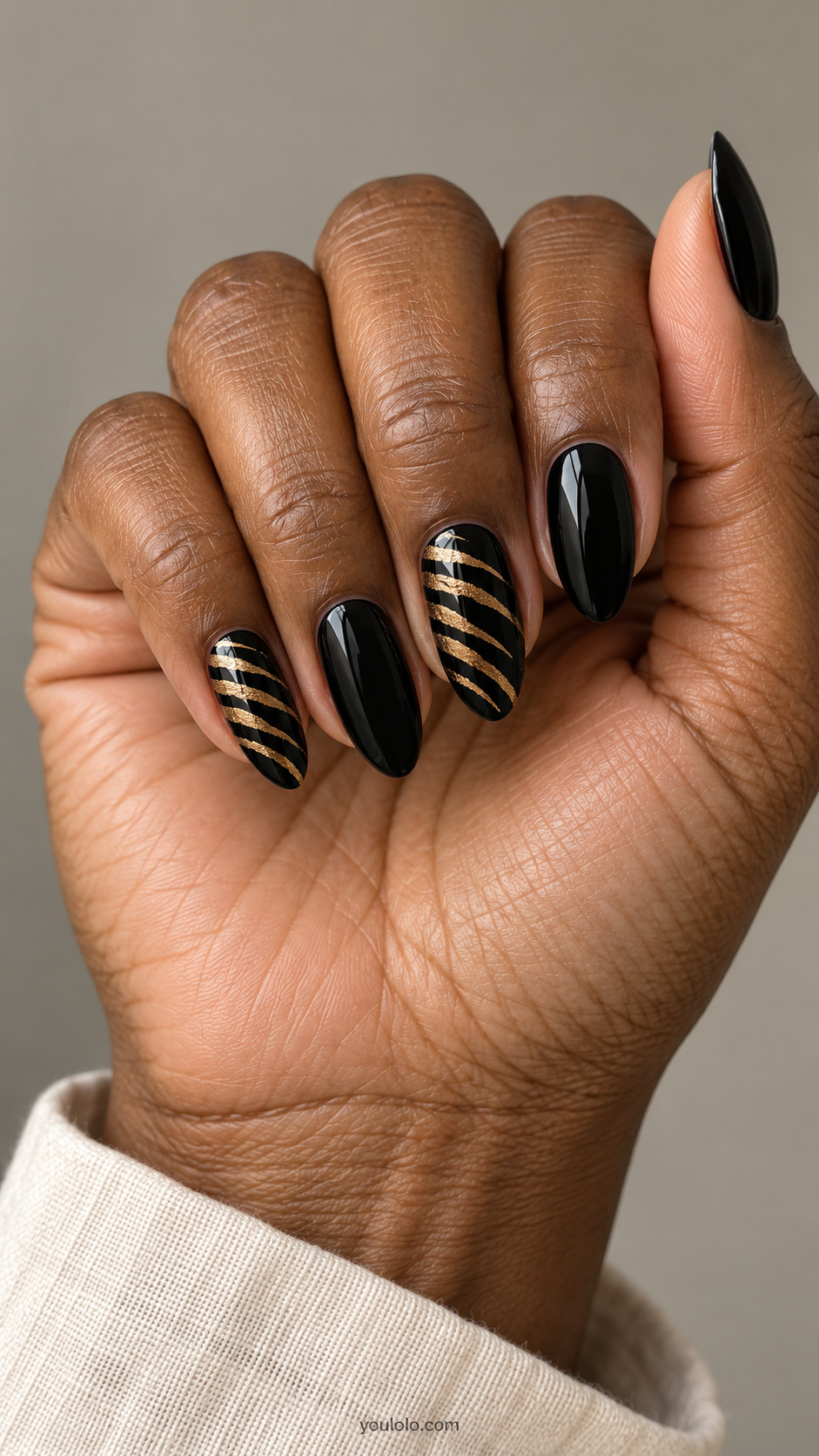 Black almond nails with tapered gold tiger stripes on two accents