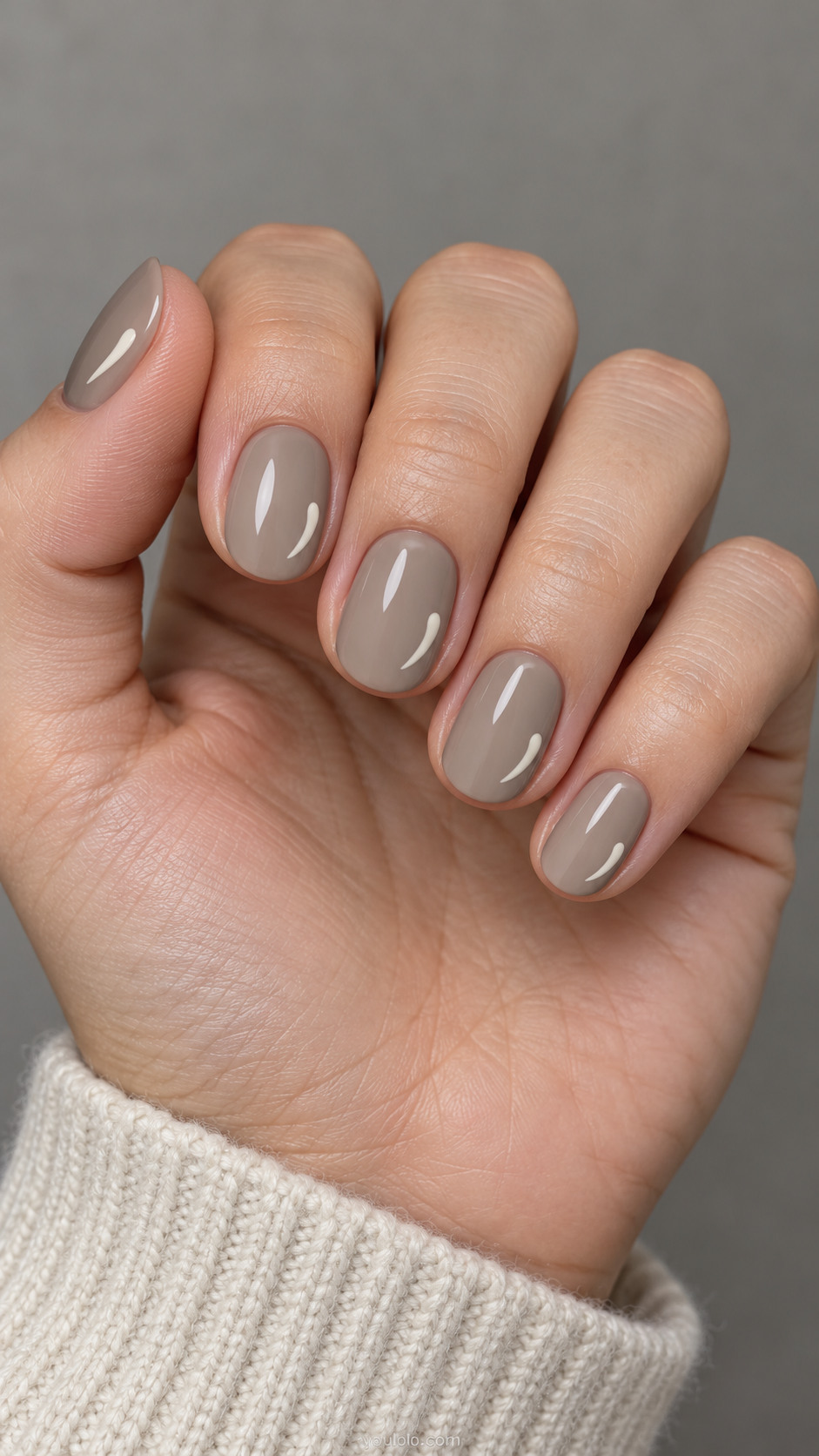 Short oval nails: greige nails with a tiny ivory comma shaped brushstroke near one side of each nail, all flat.