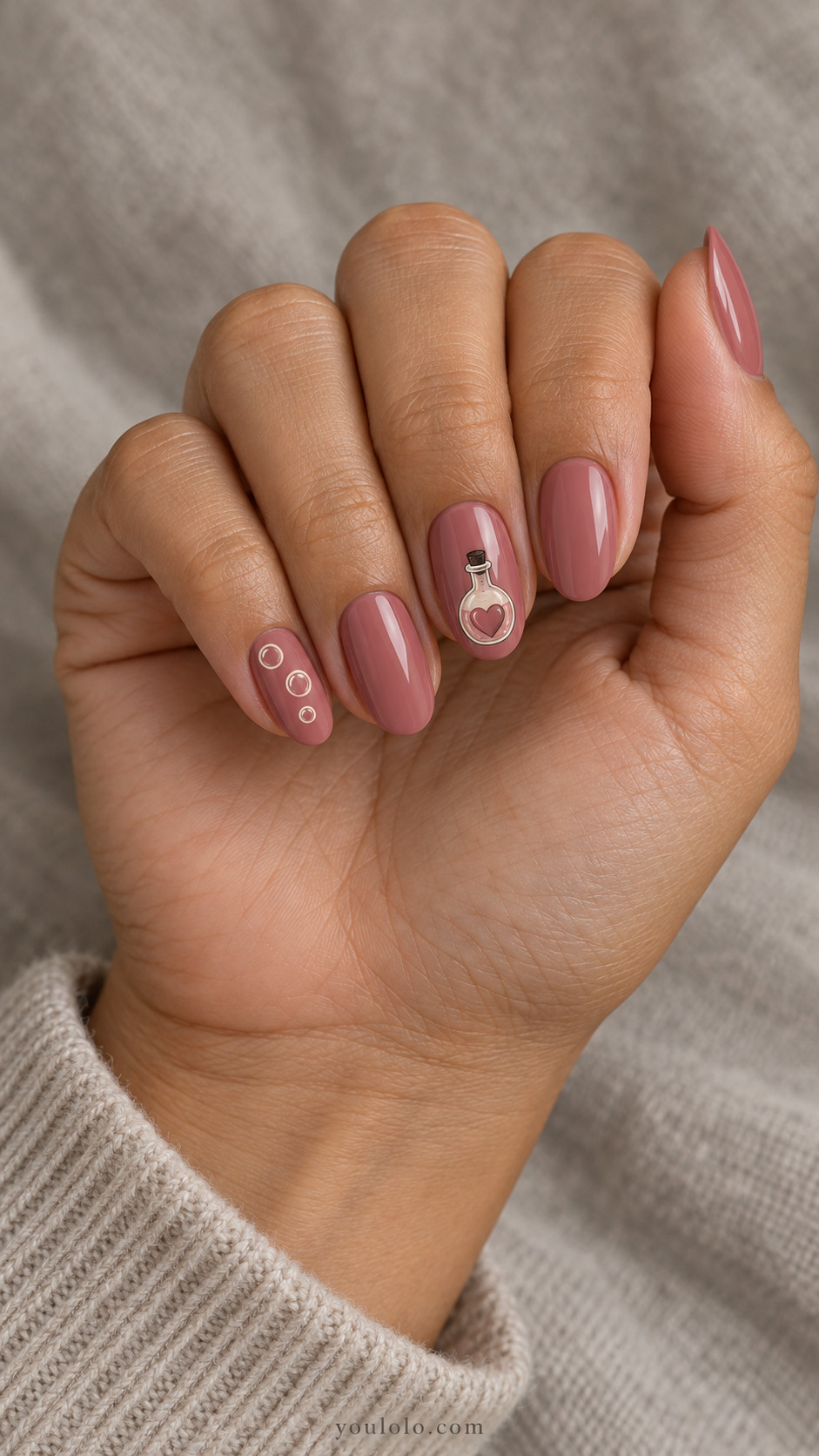Dusty rose oval nails with a small potion bottle and cream bubbles