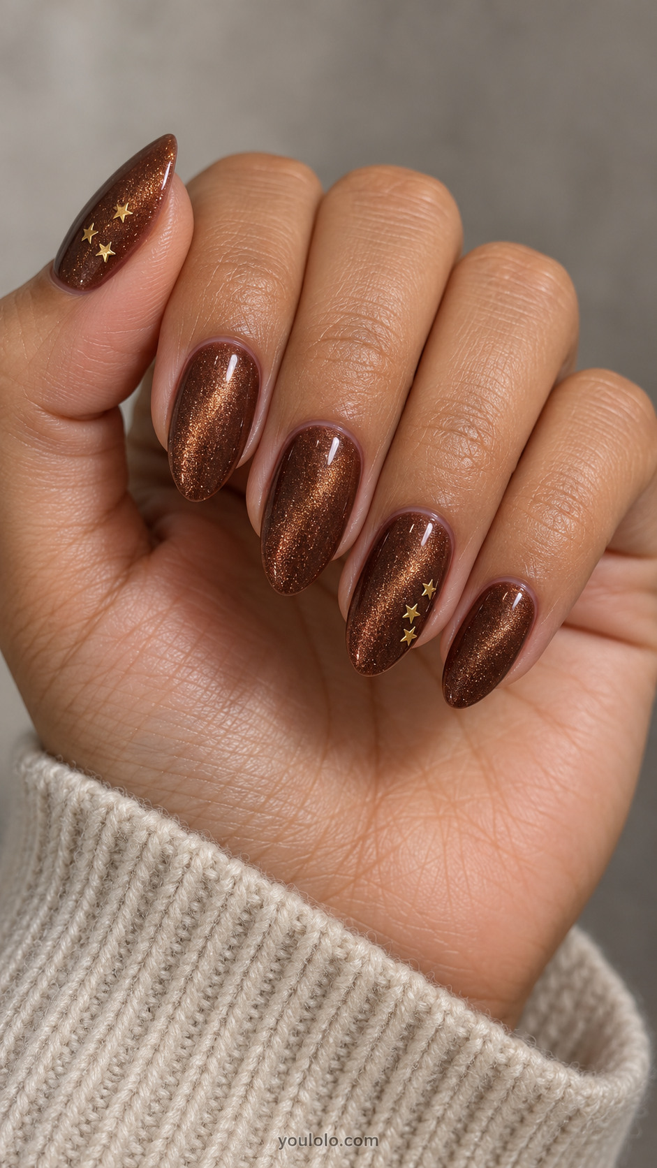 Medium almond nails: rich cinnamon brown magnetic velvet nails, ring and thumb each three tiny flat gold five-point star sequins clustered on one side, others plain.