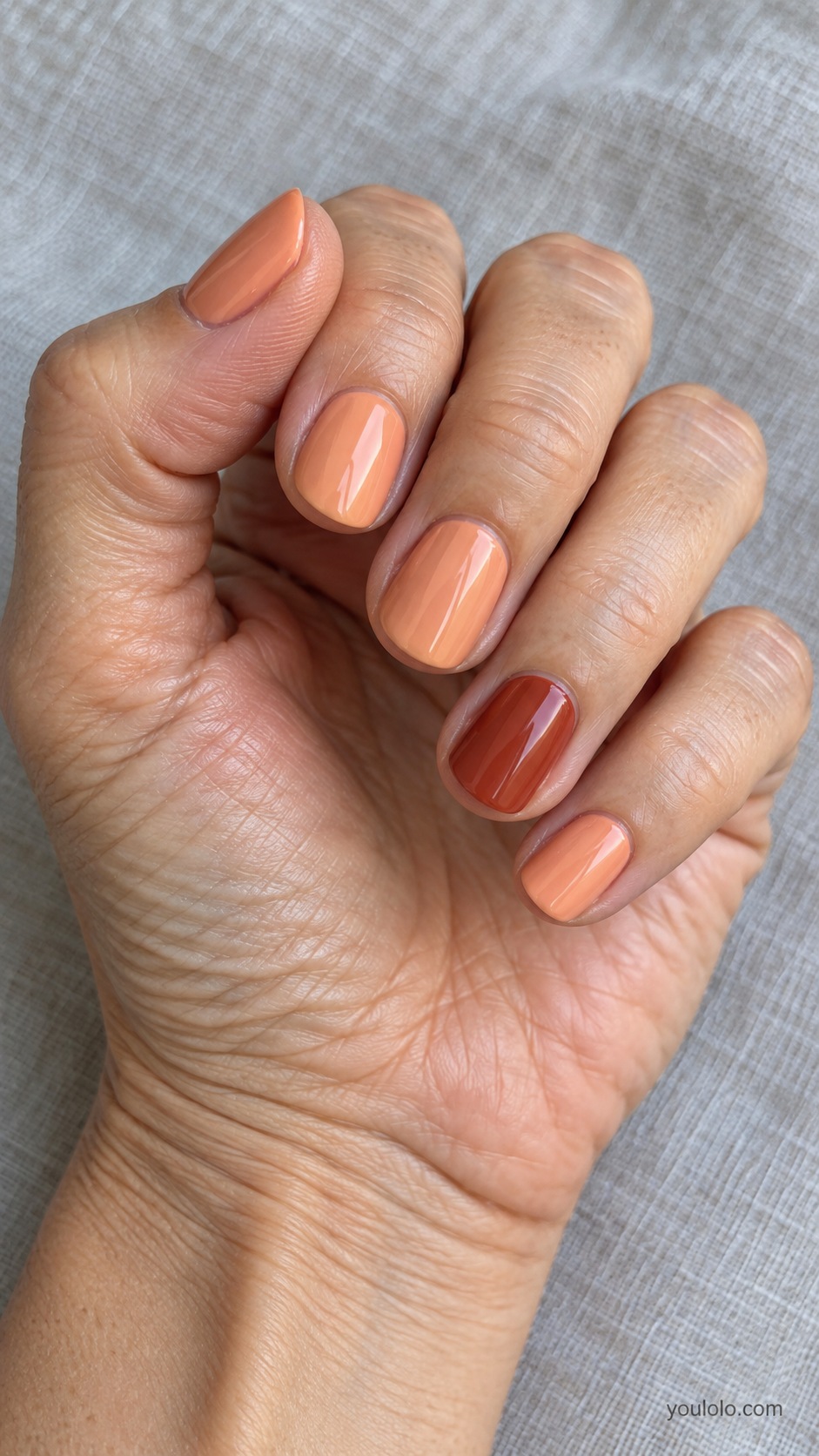 Short round nails muted apricot cream four nails one ring nail brick red cream