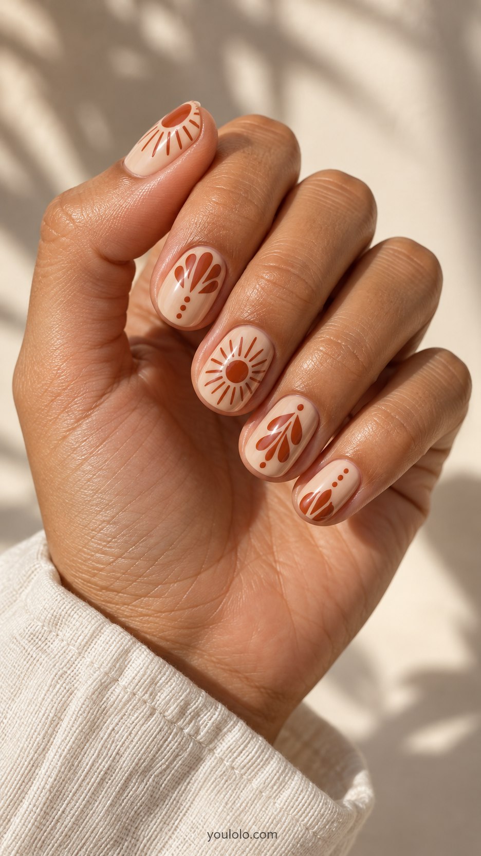 Terracotta Pottery Motifs: short oval creamy beige nails, painted terracotta sunburst and geometric petal motifs, smooth finish