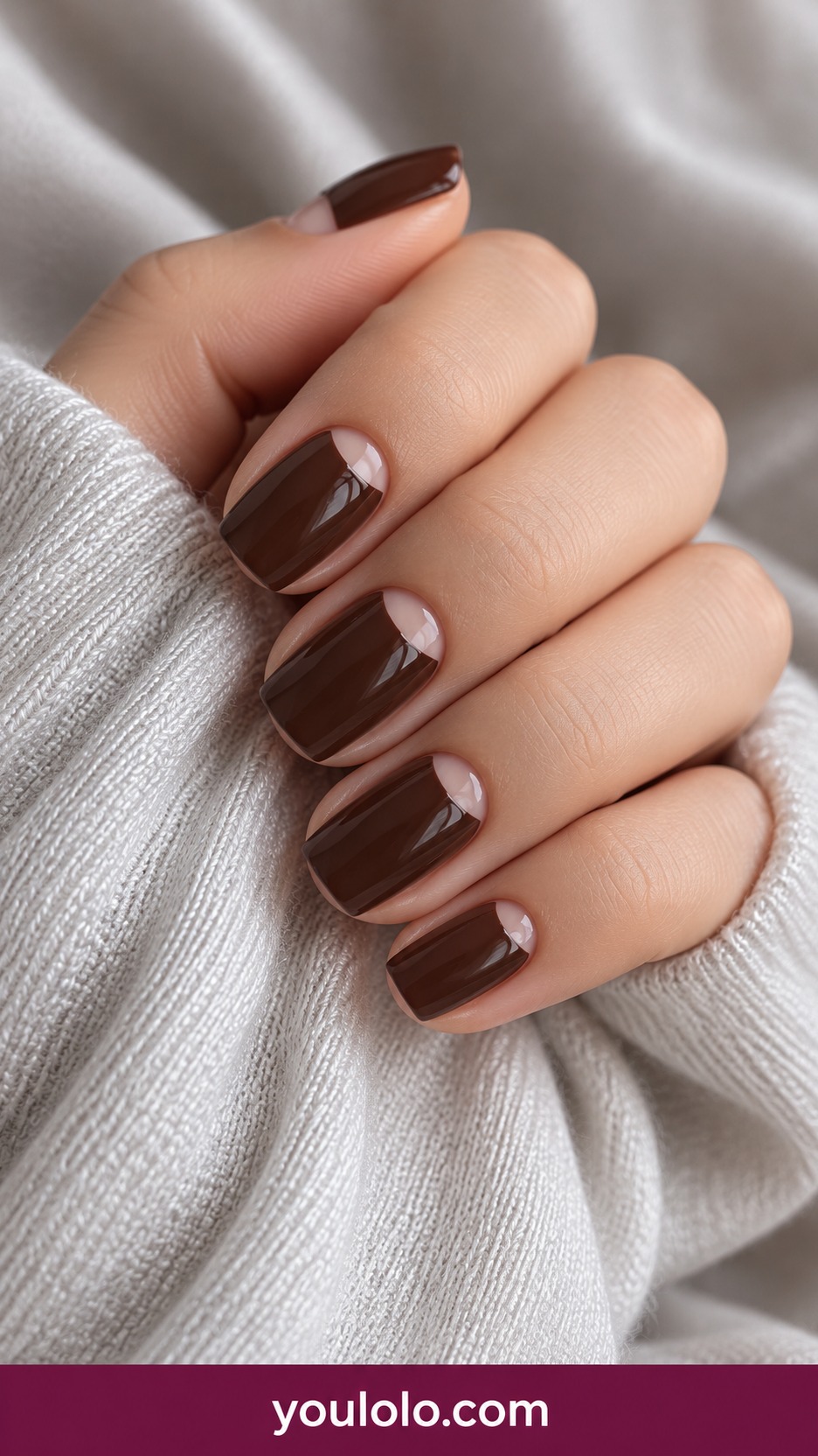 Short squoval glossy espresso brown nails with small nude half moon at base on a naturally curled young adult hand