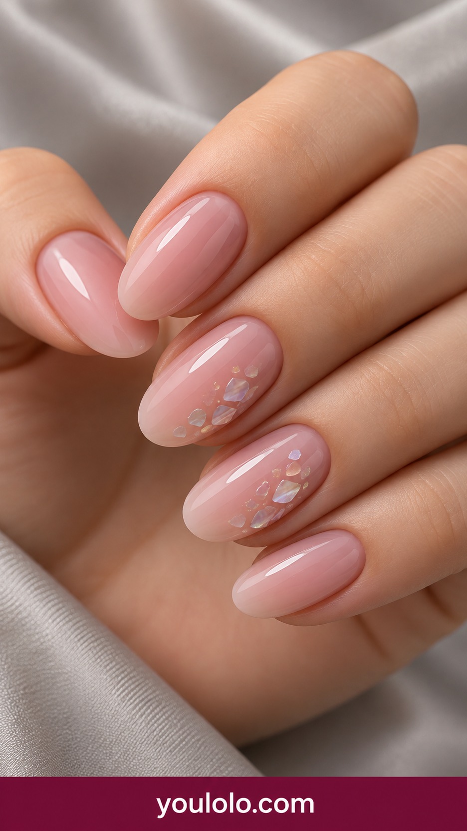 Medium oval milky pink nails with tiny flat translucent iridescent shell fragments on two accent nails, smooth glossy surface on a naturally curled young adult hand
